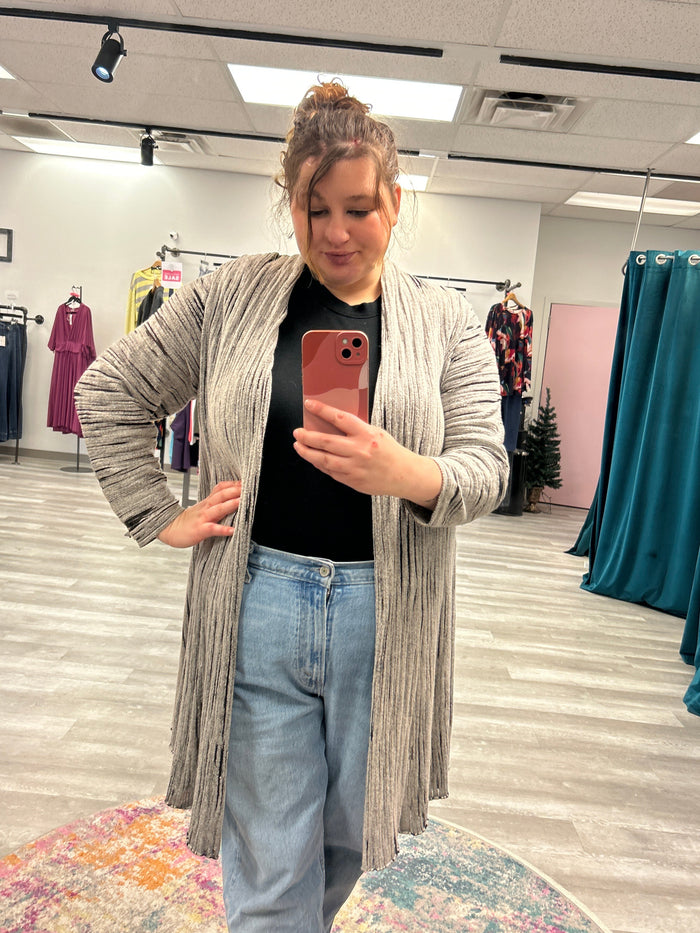 Person taking a mirror selfie in a store with clothing racks in the background