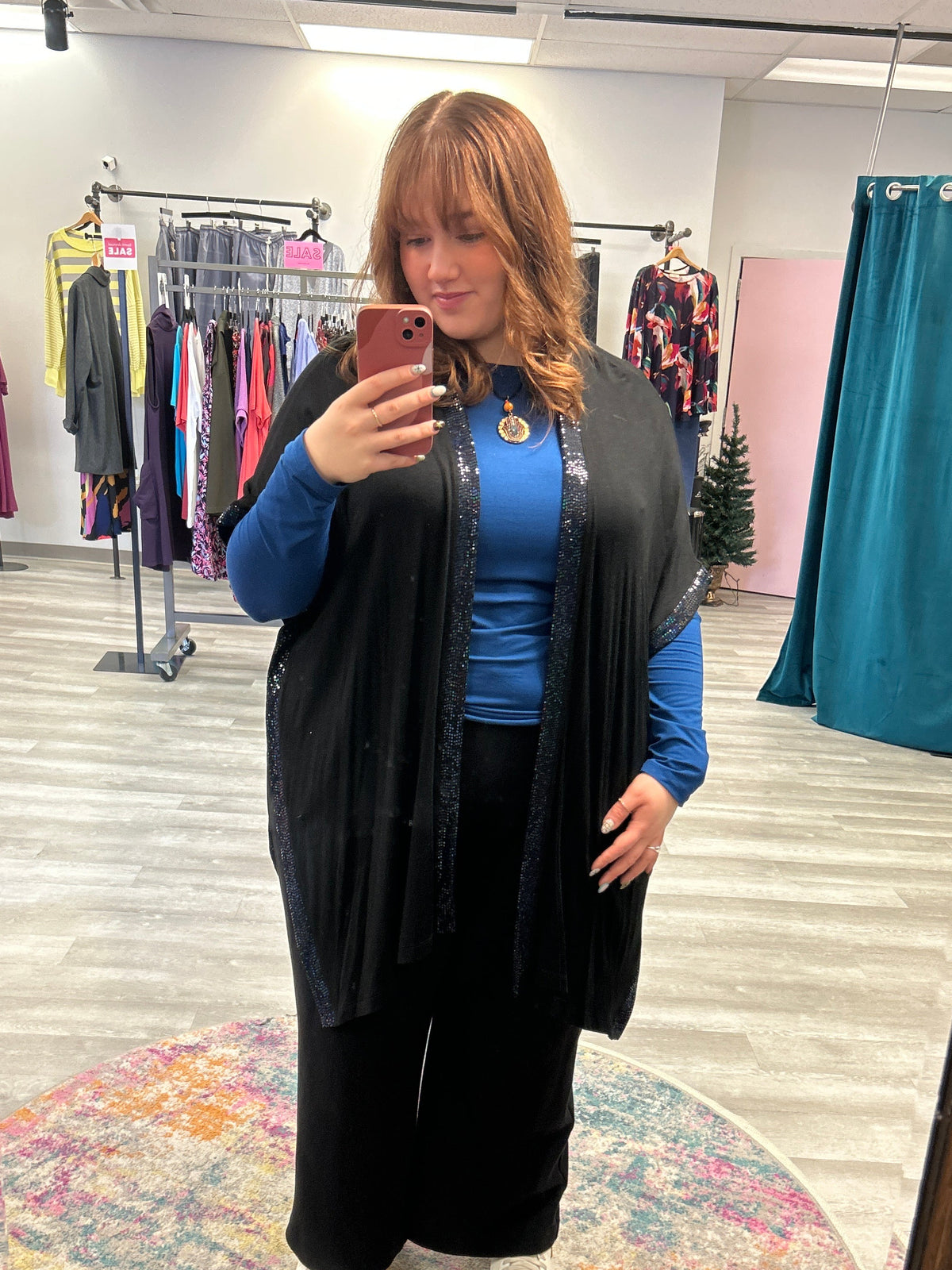 Person wearing a blue jacket and black coat standing in front of a mirror.