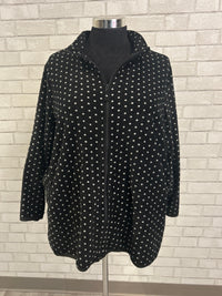 Black polka dot dress on a hanger against a tiled wall background