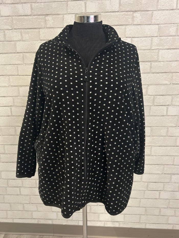 Black polka dot dress on a hanger against a tiled wall background