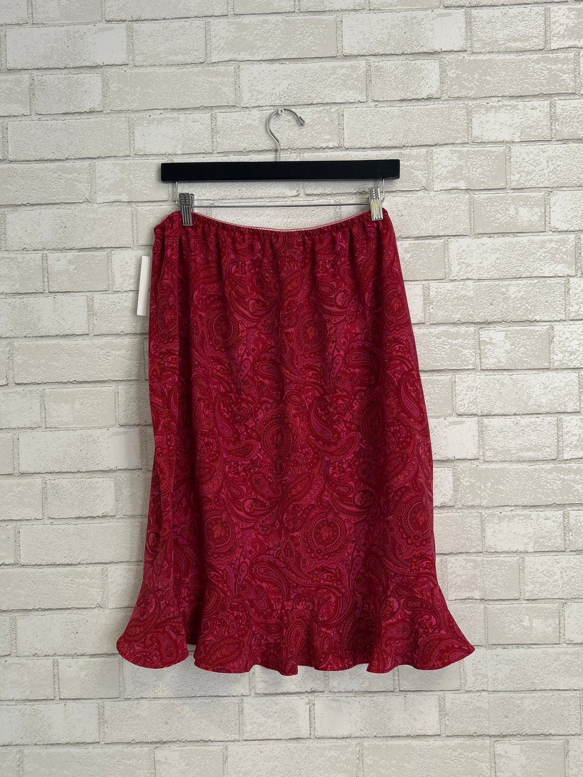 Red patterned skirt on a hanger against a tiled wall background