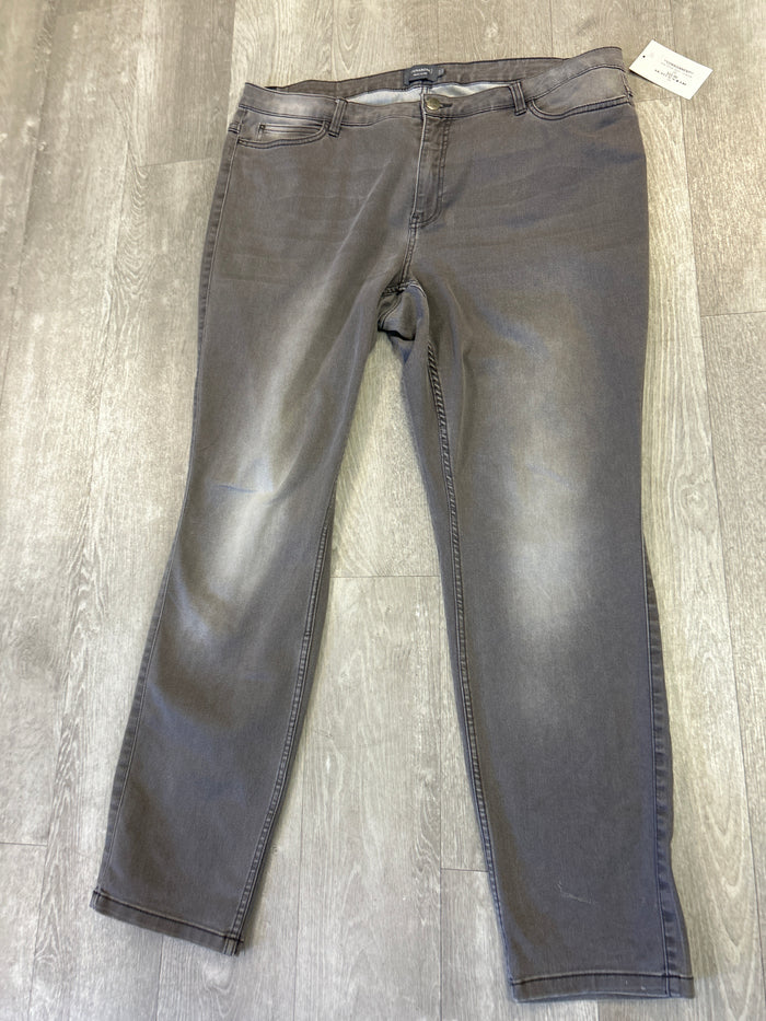 Black jeans laid flat on a wooden floor with a tag attached.