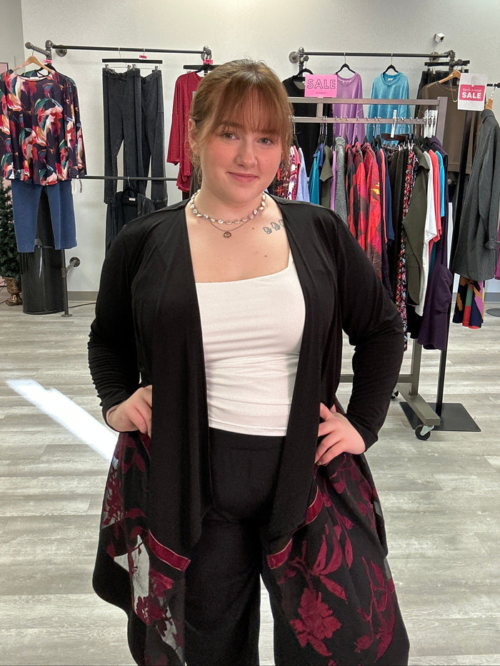 Woman standing in a clothing store with racks of clothes in the background