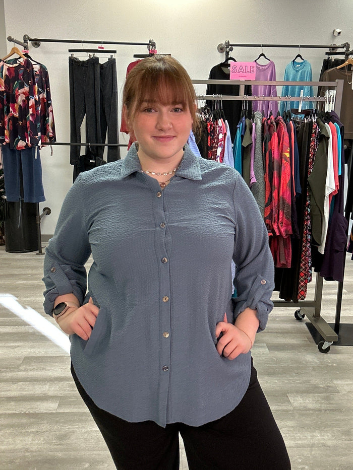 Person standing in a clothing store with racks of clothes in the background